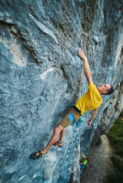 Jovem homem forte escalando rota desafiadora em um alto penhasco de calcário vertical . — Fotografia de Stock
