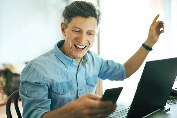 Portrait d'un homme heureux et excité utilisant le téléphone et l'ordinateur portable à la maison — Photo