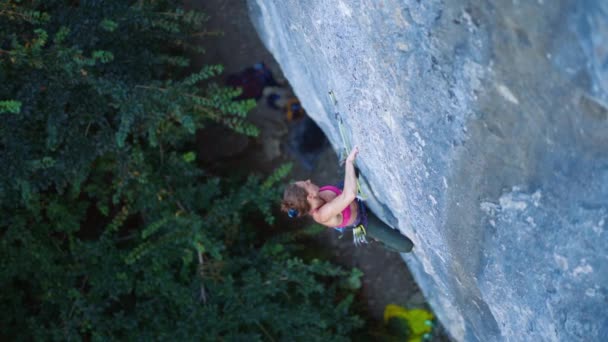 Vista superior mulher alpinista escalada na rota do esporte difícil, alpinista descansando e giz mãos penduradas no penhasco . — Vídeo de Stock