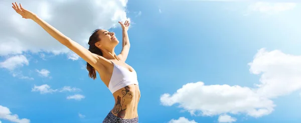 Happy smiling woman with tanned slim body and tattoo posing against blue sky. — Stock Photo, Image