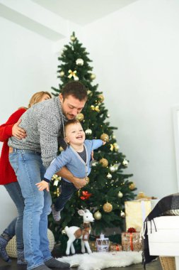 Noel ailesi evde birlikte vakit geçiriyor. Babam evdeki Noel ağacının yanında oğluyla oynuyor..