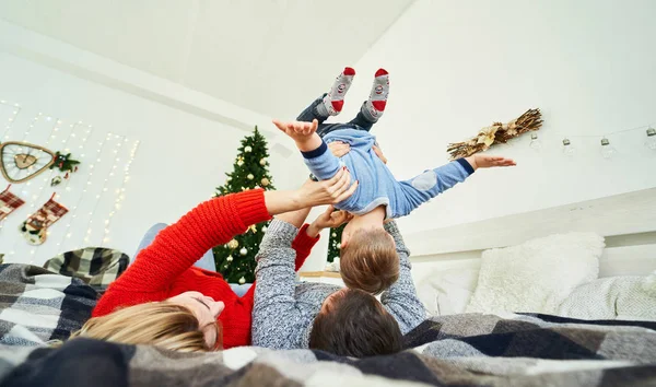 ครอบครัวคริสต์มาสใช้เวลาอยู่ด้วยกันที่บ้าน นอนอยู่บนเตียงใกล้ต้นคริสต์มาส . — ภาพถ่ายสต็อก