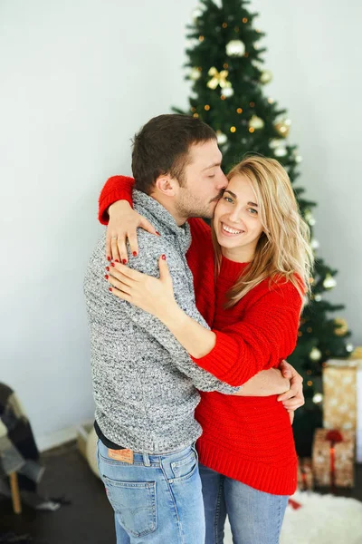Pareja romántica enamorada abrazándose, besándose cerca del árbol de Navidad en casa . —  Fotos de Stock