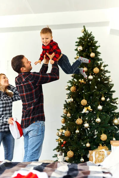 Julefamilien tilbringer tid sammen hjemme. Pappa leker med sønnen sin nær juletreet hjemme. . – stockfoto