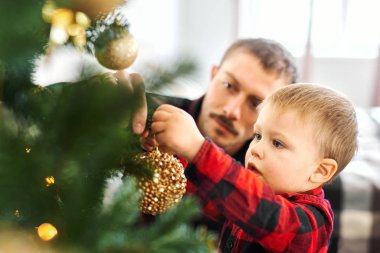 Baba ve oğul Noel arifesinde Noel ağacı süslüyorlar..