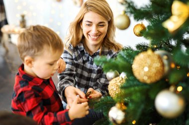 Anne ve oğul Noel arifesinde birlikte Noel ağacı süslüyorlar..