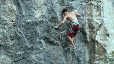 Arkaya bakan genç kaslı adam kaya tırmanışçısı zorlu bir spor rotasına tırmanıyor dikey bir uçurumda