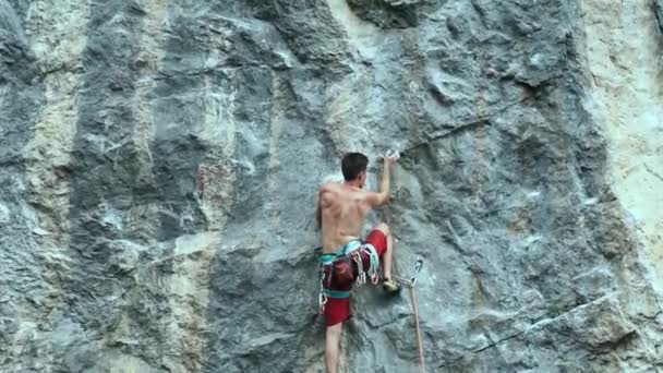 Joven hombre fuerte escalador de roca cuidadosamente subiendo en un acantilado, la búsqueda, el alcance y agarre de retención . — Vídeos de Stock