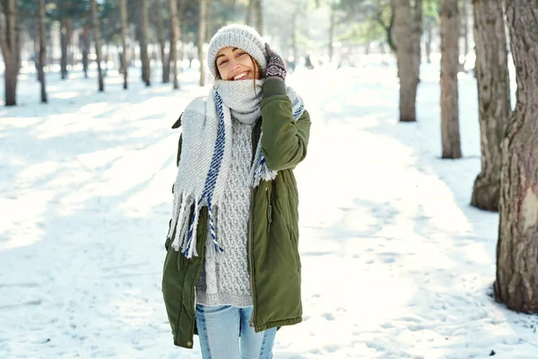 Portrait extérieur d'hiver d'une drôle de femme souriante en chapeau de laine et longue écharpe chaude au parc enneigé — Photo