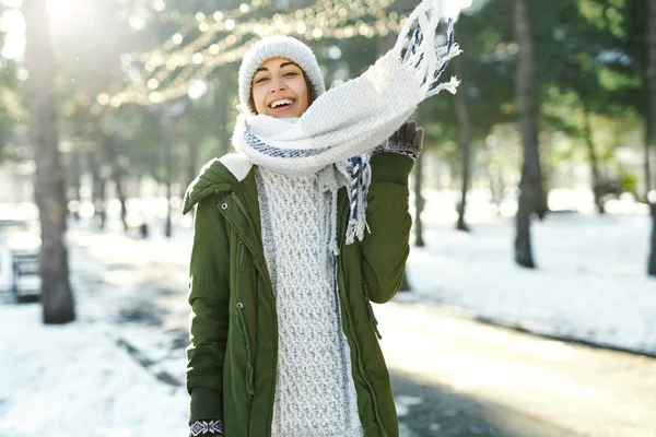 Winter portret van grappige vrouw in wollen hoed en lange warme sjaal rommelen, lachen en plezier hebben in besneeuwde winter park — Stockfoto