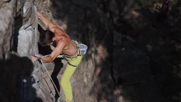 Athletic man rock climber climbs on a cliff, reaching and gripping hold. — Stock Video