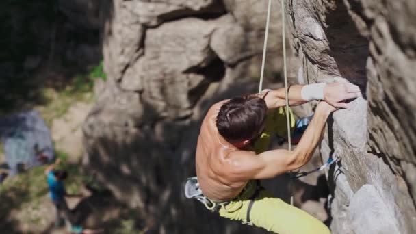 Athletic man rock climber climbs on a cliff using quickdraw — Stock Video