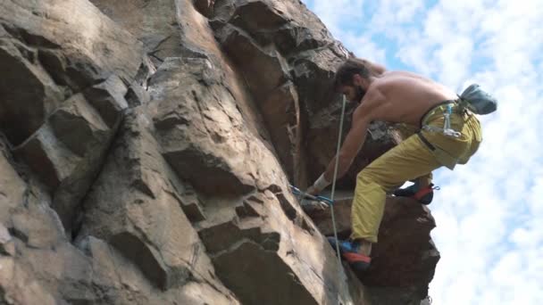 Momenti e dettagli di arrampicata al rallentatore. uomo atletico arrampicatore di roccia con busto nudo sale su una scogliera — Video Stock