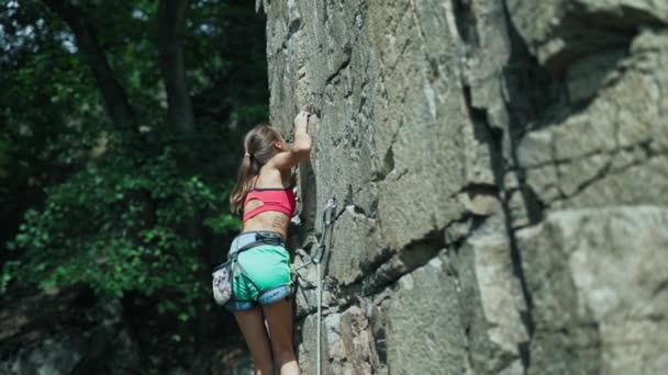 Young slim muscular woman rockclimber climbing on tough sport route, climber makes a hard move. — Stock Video