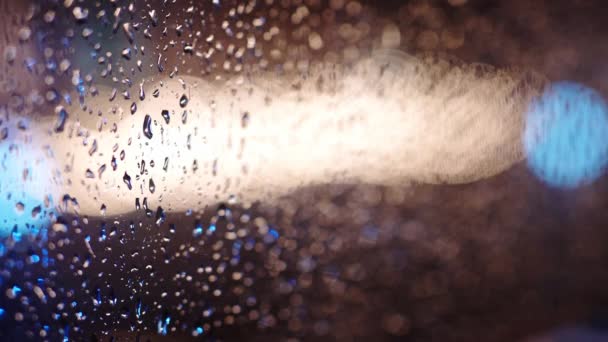 Färgglada regn droppar på fönsterglas — Stockvideo