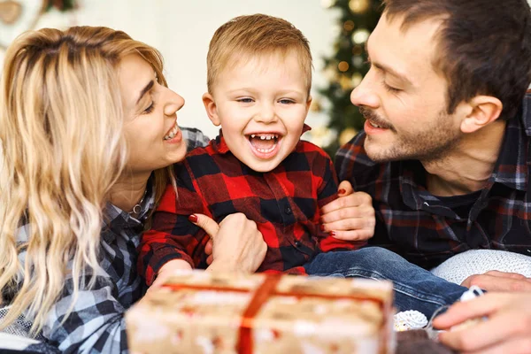 พ่อแม่หนุ่ม ๆ ให้ของขวัญคริสต์มาสกับลูกชายในเช้าวันคริสต์มาสบนเตียง . — ภาพถ่ายสต็อก