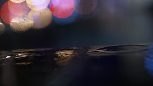 Closeup Rain drops Falling On puddle with lights reflection on city sidewalk. — Stock Video