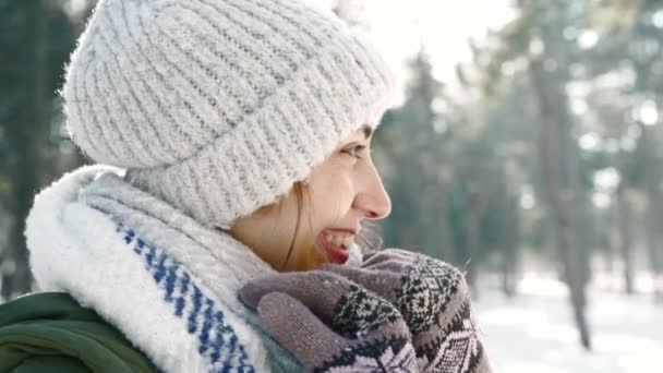 Retrato de inverno de mulher sorrindo engraçado em chapéu de lã e cachecol quente longo no parque de inverno nevado no dia ensolarado frozzy. Feliz inverno, divertindo-se — Vídeo de Stock