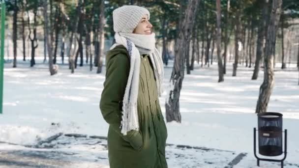 Pomalý film portrét krásné šťastný smajlík mladá žena v teplém zimním oblečení chůzi ve zasněžené zimní park v zamrzlé slunečný den. — Stock video