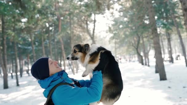 Retrato emocional del hombre feliz en ropa de invierno cálido, emrasing su mascota en el parque de invierno nevado en el día soleado helado. Feliz tiempo juntos. — Vídeo de stock