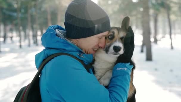 Retrato emocional do homem feliz em roupas quentes de inverno, emrasing seu animal de estimação no parque de inverno nevado no dia ensolarado gelado. Feliz tempo juntos — Vídeo de Stock