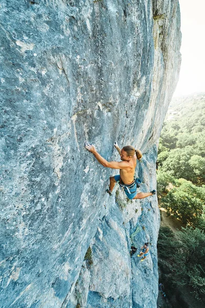 Sterk muskuløs fjellklatrer med naken torso som klatrer dynamisk på en vertikal klippe , – stockfoto