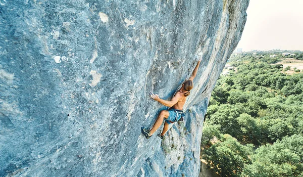 Vista superior forte homem muscular escalador de rocha com tronco nu escalando dinamicamente em um penhasco vertical , — Fotografia de Stock