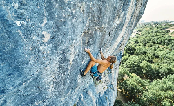 Forte uomo muscoloso arrampicatore su roccia con busto nudo salendo dinamicamente su una falesia verticale , — Foto Stock