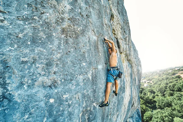 Forte uomo muscoloso arrampicatore su roccia con busto nudo salendo dinamicamente su una falesia verticale , — Foto Stock
