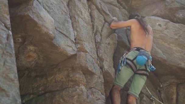 Homem atraente rockclimber sobe em um penhasco de granito, atingindo e segurando . — Vídeo de Stock