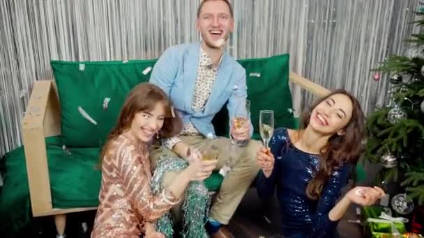 Riprese al rallentatore di due belle ragazze incredibili in abiti alla moda lucido e l'uomo alla moda che festeggia il nuovo anno, compleanno e tiene i calici di champagne . — Video Stock