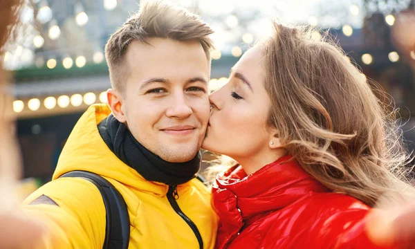 Joven pareja romántica en el amor haciendo selfie, sonrisa a la cámara, mujer besándose en la mejilla su novio . —  Fotos de Stock