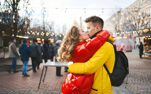 Tineri cuplu romantic în dragoste sărutat, îmbrățișare, mers pe jos pe stradă, purtând în jachete luminoase jos. Urbanism . — Fotografie, imagine de stoc