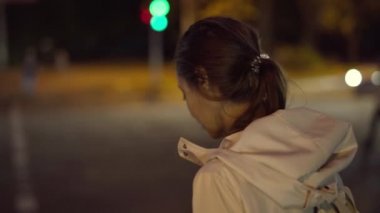 Güzel, gülümseyen genç bir kadın gece vakti şehir dışında yürüyor..