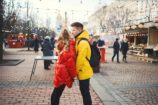 Ritratto di giovane coppia romantica innamorata baciare, abbracciare, camminare per strada, indossarsi in piumini luminosi. background urbano. — Foto Stock