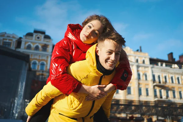 Güneşli bir günde şehir caddesinde yürüyen mutlu genç çift, birlikte eğleniyorlar. Genç adam kız arkadaşını omuzlarında taşıyor..