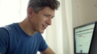 Evde dizüstü bilgisayara bakan yakışıklı bir adamın duygusal portresi..