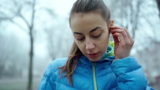 Giovane donna attraente utilizzando auricolari wireless durante il jogging — Video Stock