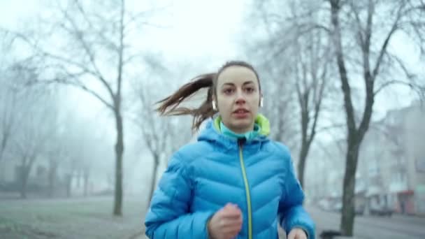 Slow motion ung sportig kvinna som springer med trådlösa hörlurar. — Stockvideo