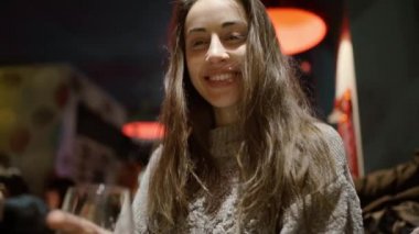 Pov mutlu, uzun saçlı, çekici bir kadın barda bira içiyor ve şerefe içiyor.