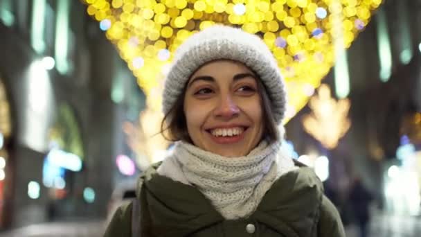 Closeup night portrait of happy laughing young woman wearing warm winter clothes, woolen knitted scarf and hat. — Stock Video