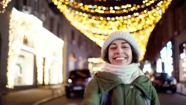 Closeup night portrait of happy laughing young woman wearing warm winter clothes, woolen knitted scarf and hat. — Stock Video