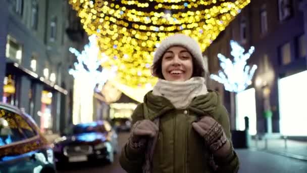Happy laughing young woman wearing warm winter clothes fast playfully walking night city street — Stock Video