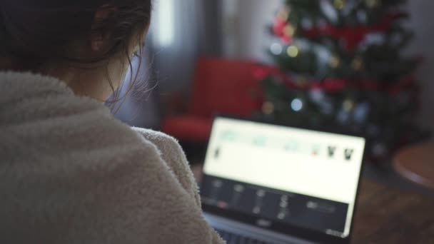 Οπίσθια όψη του γυναικείου ελεύθερου επαγγελματία που κάθεται στο σπίτι και εργάζεται χρησιμοποιώντας φορητό υπολογιστή — Αρχείο Βίντεο