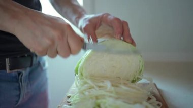 Ağır çekim adam vejetaryen salatası için lahanayı bıçakla kesiyor.