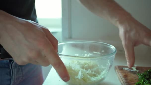 Hombre manos poniendo hierbas verdes picadas en tazón de cristal — Vídeos de Stock