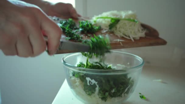 Man hands putting chopped green herbs in glass bowl — Stock Video