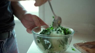 Sebzeleri bir kasede karıştıran adam, salata pişiriyor..