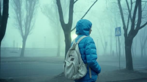 Молода спортивна жінка в синій куртці з капюшоном і міським рюкзаком — стокове відео