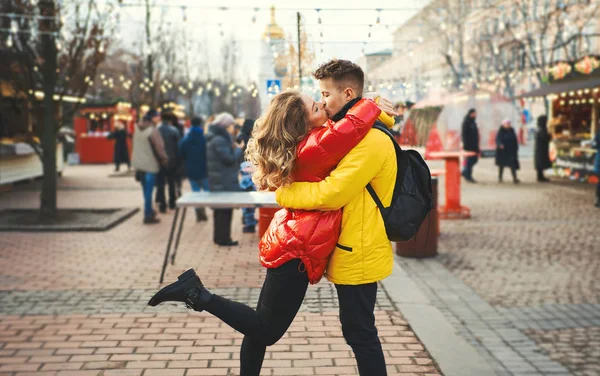 Romantický zamilovaný pár, líbající se, objímající se, procházející se po ulici, oblečený v pestrých bundách. městské pozadí. — Stock fotografie